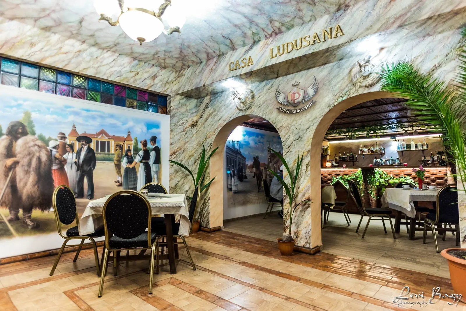 Sala restaurantului Casa Ludușană, cu arcade și picturi murale